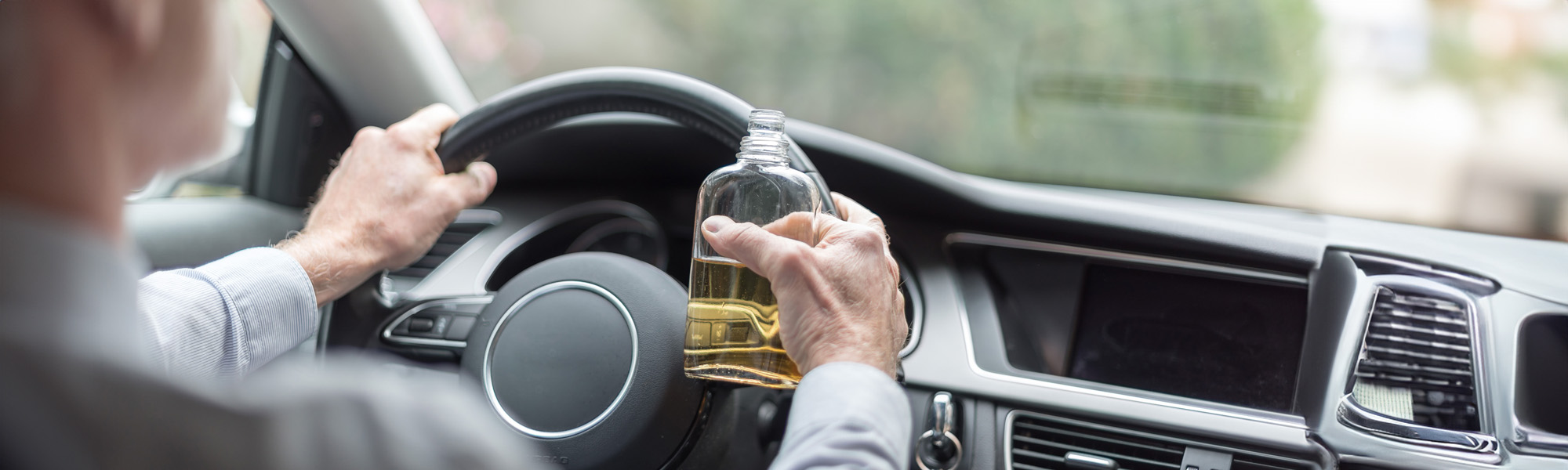 man driving with a liquor bottle