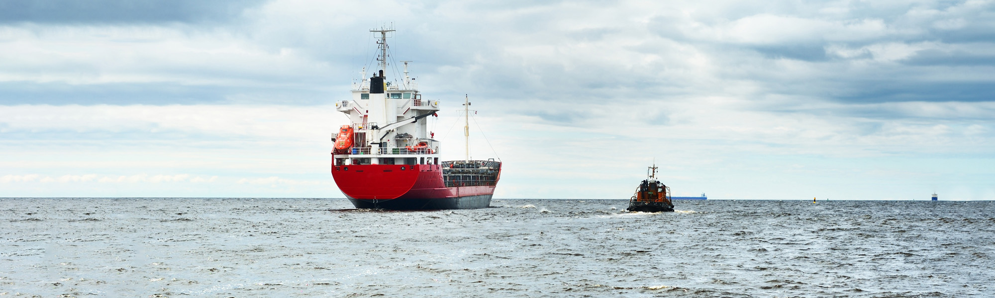 general cargo ship next to a tugboat in a open sea