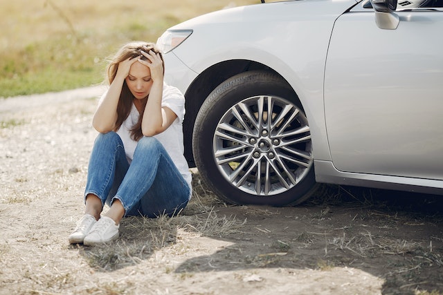 woman stressed out sitting near front of car